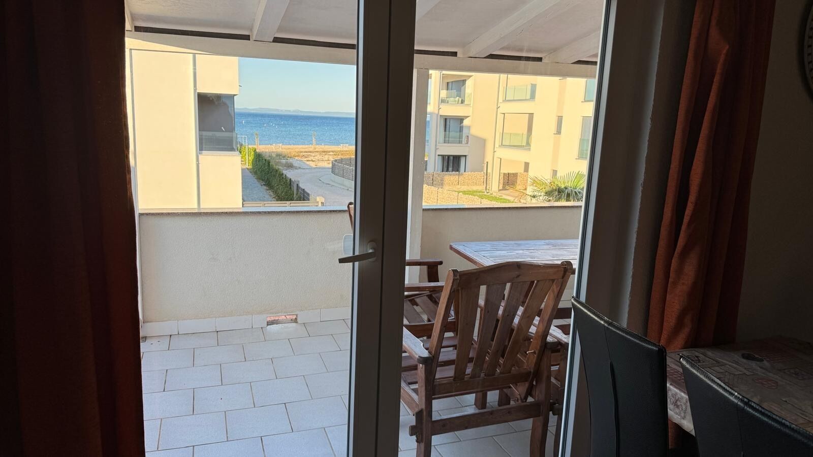A balcony with a view of the sea and adjacent buildings.