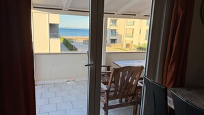 Een balkon met uitzicht op zee en omliggende gebouwen.