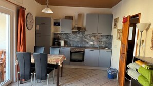 Een kleine keuken met een eethoek, een klok aan de muur en een raam met gordijnen.