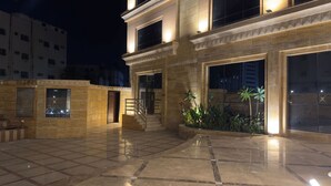 Um pátio bem iluminado com piso de azulejos, escadaria e uma grande janela.
