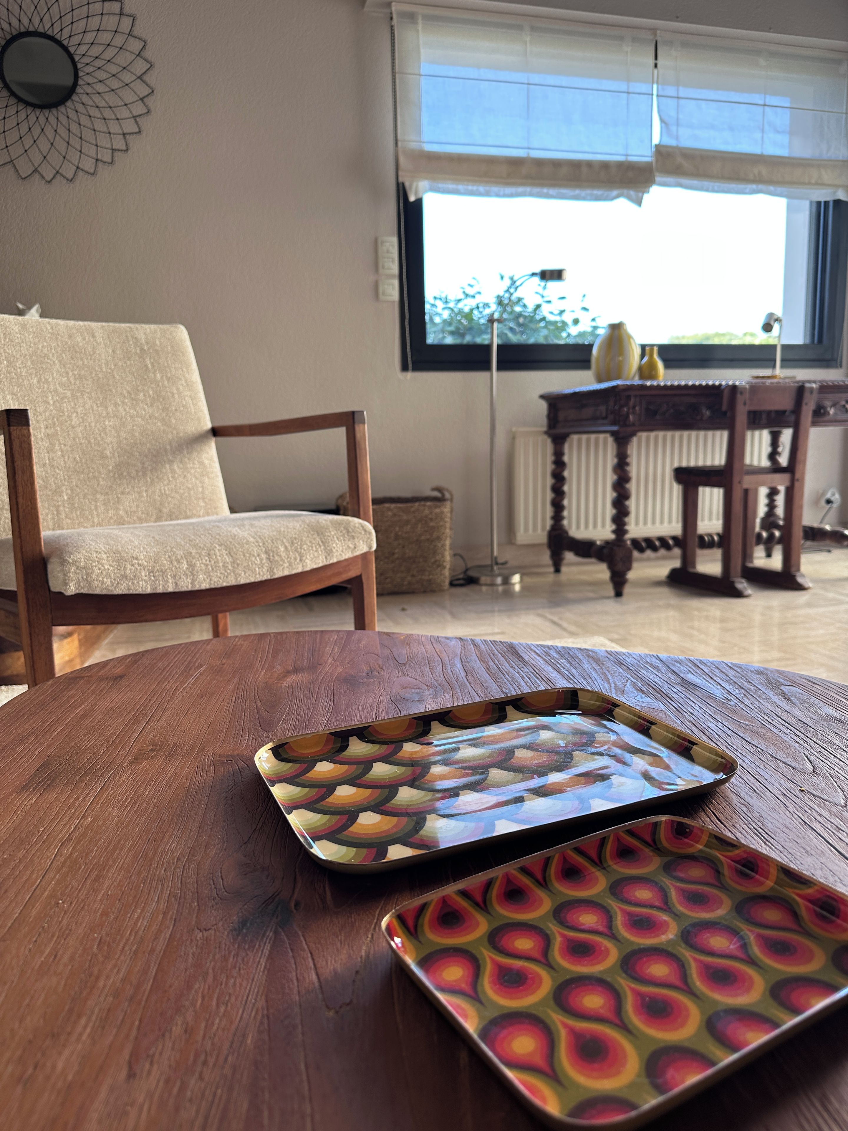 Uma mesa de madeira com uma bandeja colorida e uma cadeira com almofada.