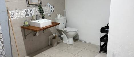 A bathroom with a toilet, sink, and a mop leaning against the wall.