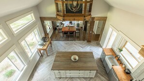 Una cocina amplia con una isla central, ventanas grandes y un comedor en entrepiso.