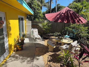 A patio area with a yellow building, outdoor furniture, and a red umbrella.