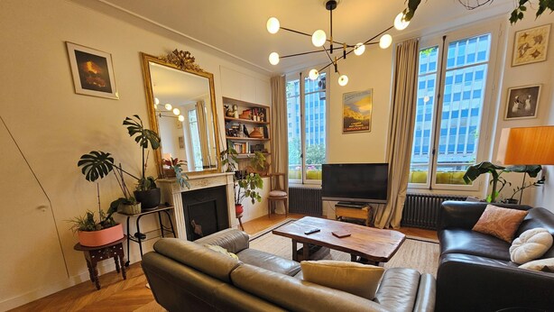 Un salon comprenant un canapé, une table basse, une cheminée, un téléviseur et de grandes fenêtres.