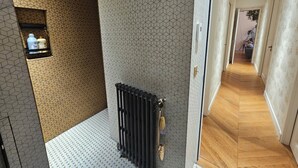 Un couloir aux murs ornés de motifs, avec un radiateur et un plancher en bois.