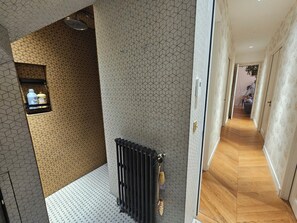 A hallway with patterned walls, a radiator, and a wooden floor. - Les Frères Montgolfier - Les Canaux - 100m² - France (Paris)