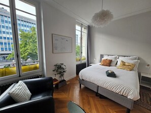 A bedroom with a large bed, a black leather sofa, a potted plant, and a map on the wall. - Les Frères Montgolfier - Les Canaux - 100m² - France (Paris)