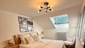 Et soveværelse med seng, natbord, lampe og et vindue med udsigt.
