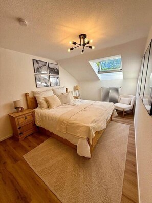 Ein Schlafzimmer mit einem Bett, einem Nachttisch, einer Lampe und einem Fenster mit Blick.