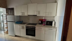 A kitchen with white cabinets, a stove, oven, microwave, and a sink. - Directly on the beach (Vir)