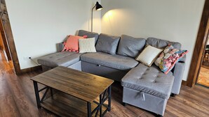 A modern living room with a sectional sofa, a wooden coffee table, and a floor lamp. - La Maison Argonnaise (Beaulieu en argonne)