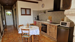 A kitchen with a dining table, chairs, a microwave, a stove, and a refrigerator. - La Maison Argonnaise (Beaulieu en argonne)