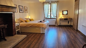 A bedroom with a bed, bedside table, lamp, window with curtains, and a mirror. - La Maison Argonnaise (Beaulieu en argonne)