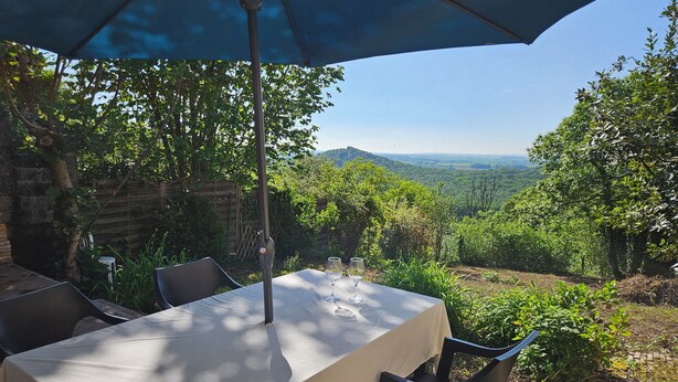 An outdoor dining area with a table, chairs, and a large umbrella. - La Maison Argonnaise (Beaulieu en argonne)