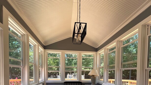 A sunroom with large windows, wicker furniture, a wooden floor, and a hanging light fixture. - Cozy luxe Durham escape (Durham)