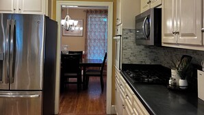A kitchen with a stainless steel refrigerator, a microwave, and a stove. There is a dining area with a table and chairs visible through a doorway. - Cozy luxe Durham escape (Durham)