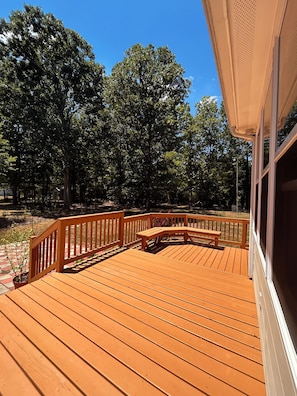 A wooden deck with a curved bench and railing, surrounded by trees.