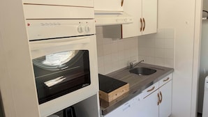 Una cucina con forno a incasso, microonde e lavello.