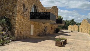 A stone building with arched windows and a balcony. - Gîte 6 personnes au Lac des Chênes (Montaigu-de-Quercy)