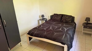 Una camera da letto con un letto, un comodino, una lampada, un armadio e un punto luce a parete.