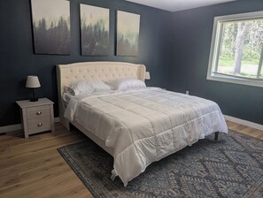 A bedroom with a bed, a nightstand, a lamp, and a window with blinds.
