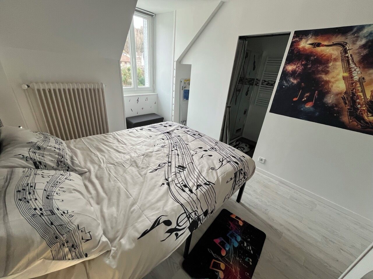 Una camera da letto con un letto, un termosifone, una finestra e un quadro appeso al muro.