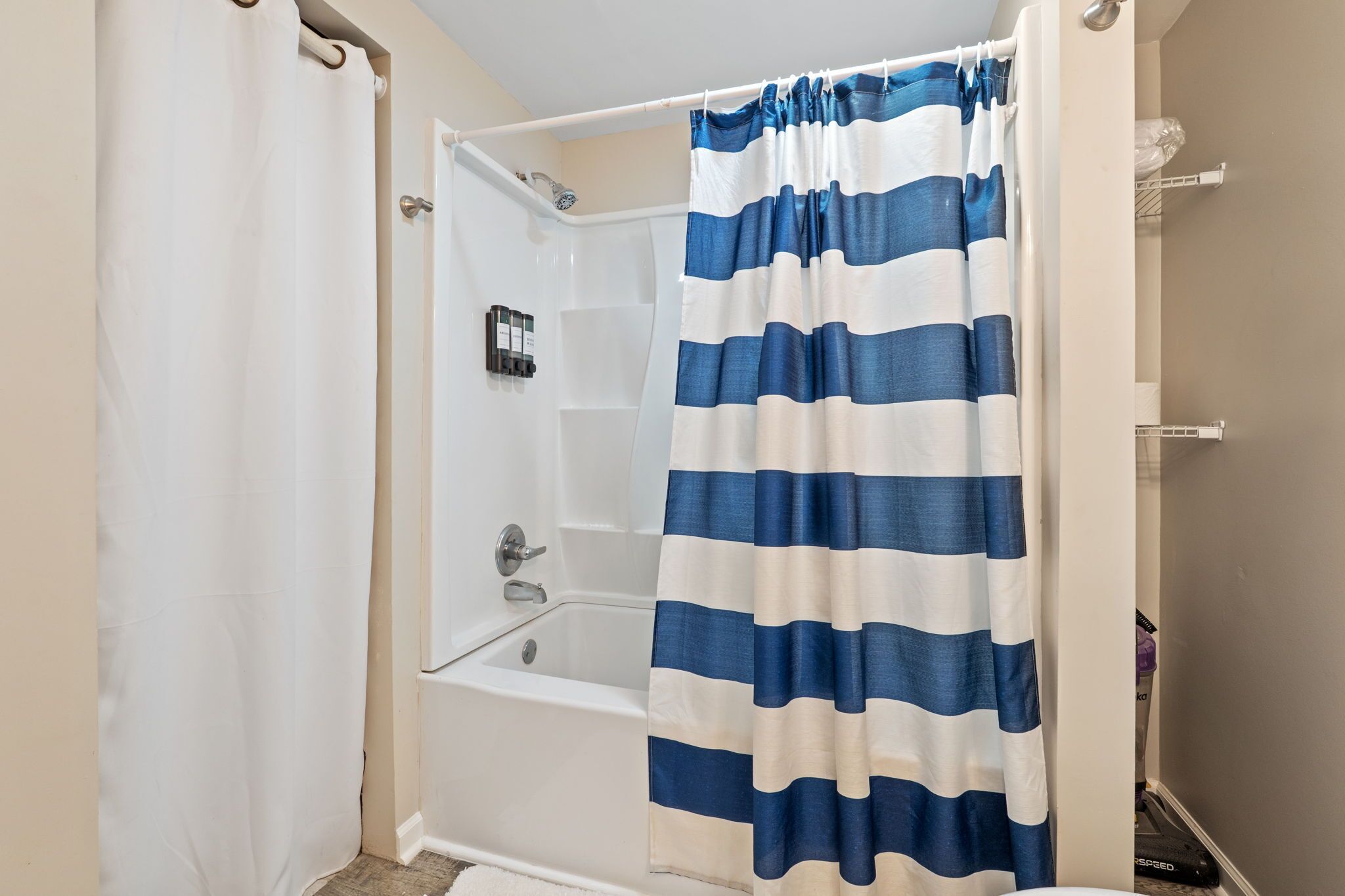 Un baño con una bañera blanca, una cortina de ducha y un perchero para toallas.