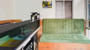 Una hall d'albergo con reception, un'area salotto imbottita in verde, una finestra con vista e una porta.