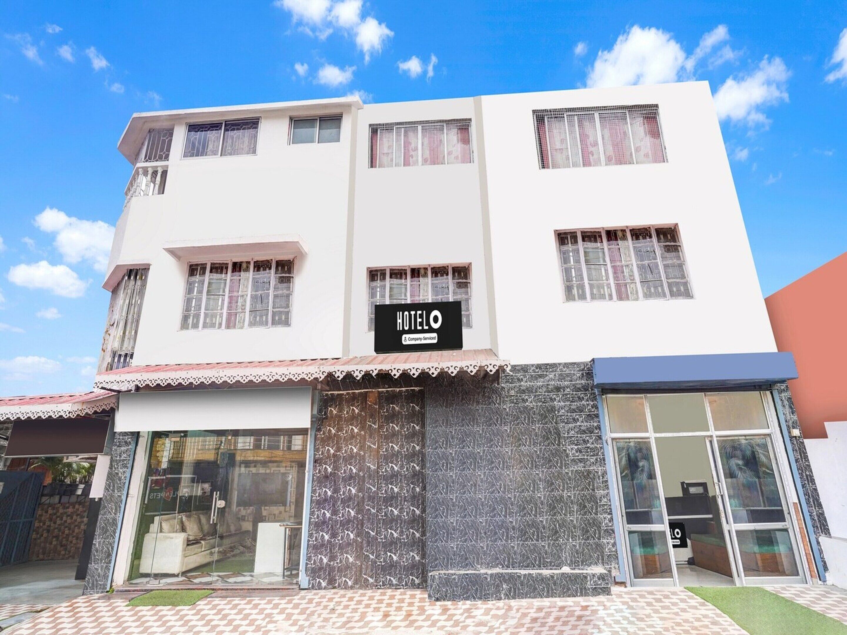 Un hôtel avec une enseigne, une entrée en verre et une façade carrelée.