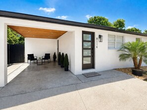 Ein modernes Haus mit überdachter Terrasse, einer Tür mit Fenster und einer Fußmatte.