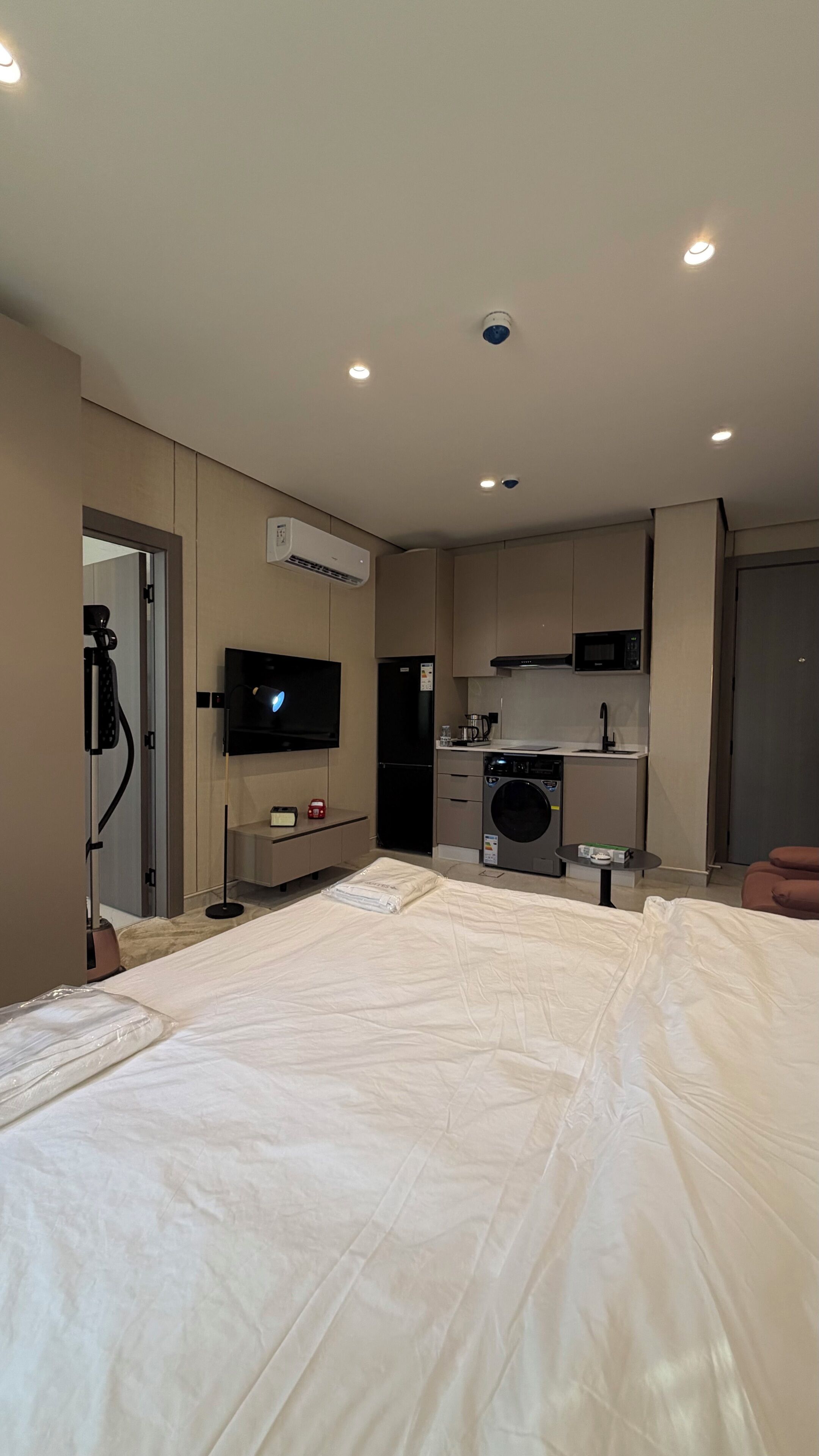 Ein Schlafzimmer mit einem großen Bett, einem Fernseher, einer Waschmaschine und einer Küchenzeile.
