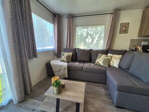 Een moderne woonkamer met een hoekbank, een salontafel en een raam met gordijnen.