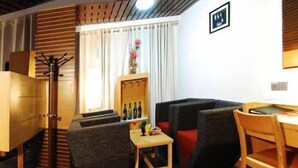 A compact living space with a sofa, a small table, a chair, a coat rack, and a cabinet. - Onn Hotel (Ludhiana)