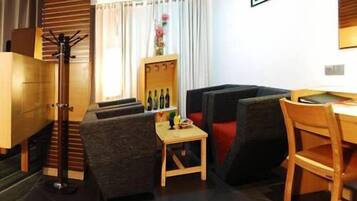 A compact living space with a sofa, a small table, a chair, a coat rack, and a cabinet.