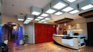 A hotel reception area with a marble floor, a red accent wall, and a modern ceiling design with recessed lighting. - Onn Hotel (Ludhiana)