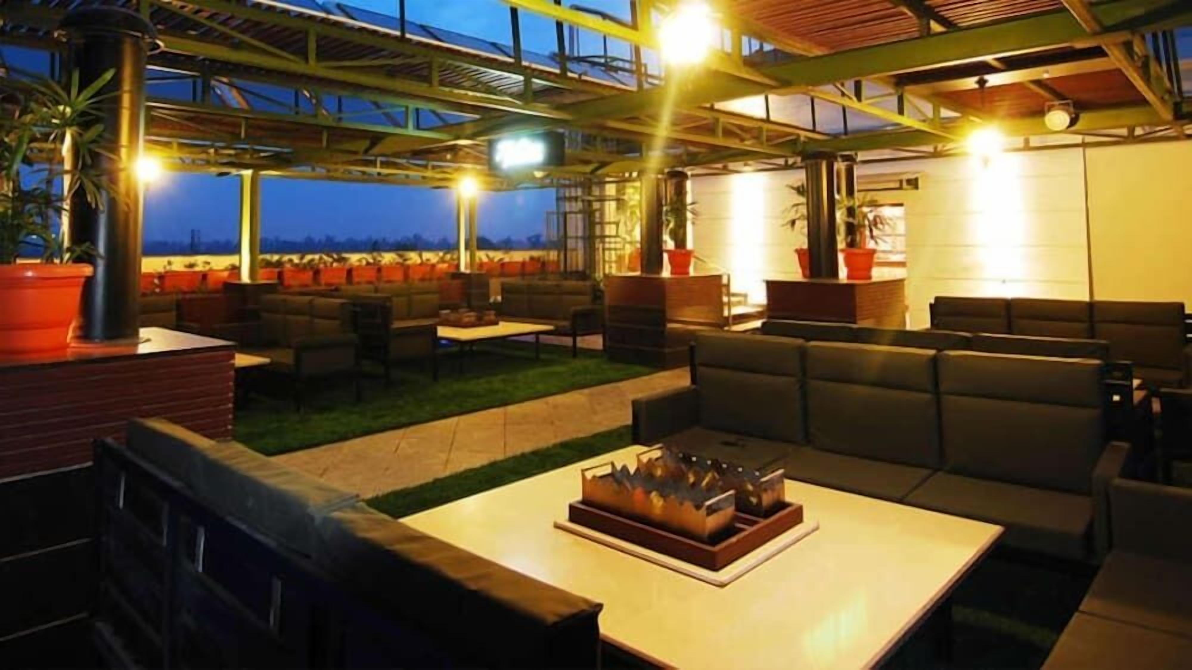 An outdoor seating area with tables and chairs, a fire pit, and potted plants.