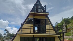 Un edificio con techo triangular, un balcón y una escalera que lleva a la entrada.