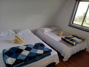 Two single beds with white linens and a blue checkered blanket on one. - Valle Cristal Cabins 🛖🏕️☕🏔️ First-Floor Rental. (Murillo)