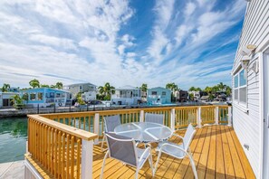 A wooden deck with a table and chairs, a pool, and a marina with boats. - Ocean Breeze Retreat w/ Dock - Keys Escape (Cudjoe Key)