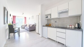 Eine moderne Küche mit weißen Schränken, einer eingebauten Mikrowelle und einem Wasserkocher auf der Arbeitsfläche.