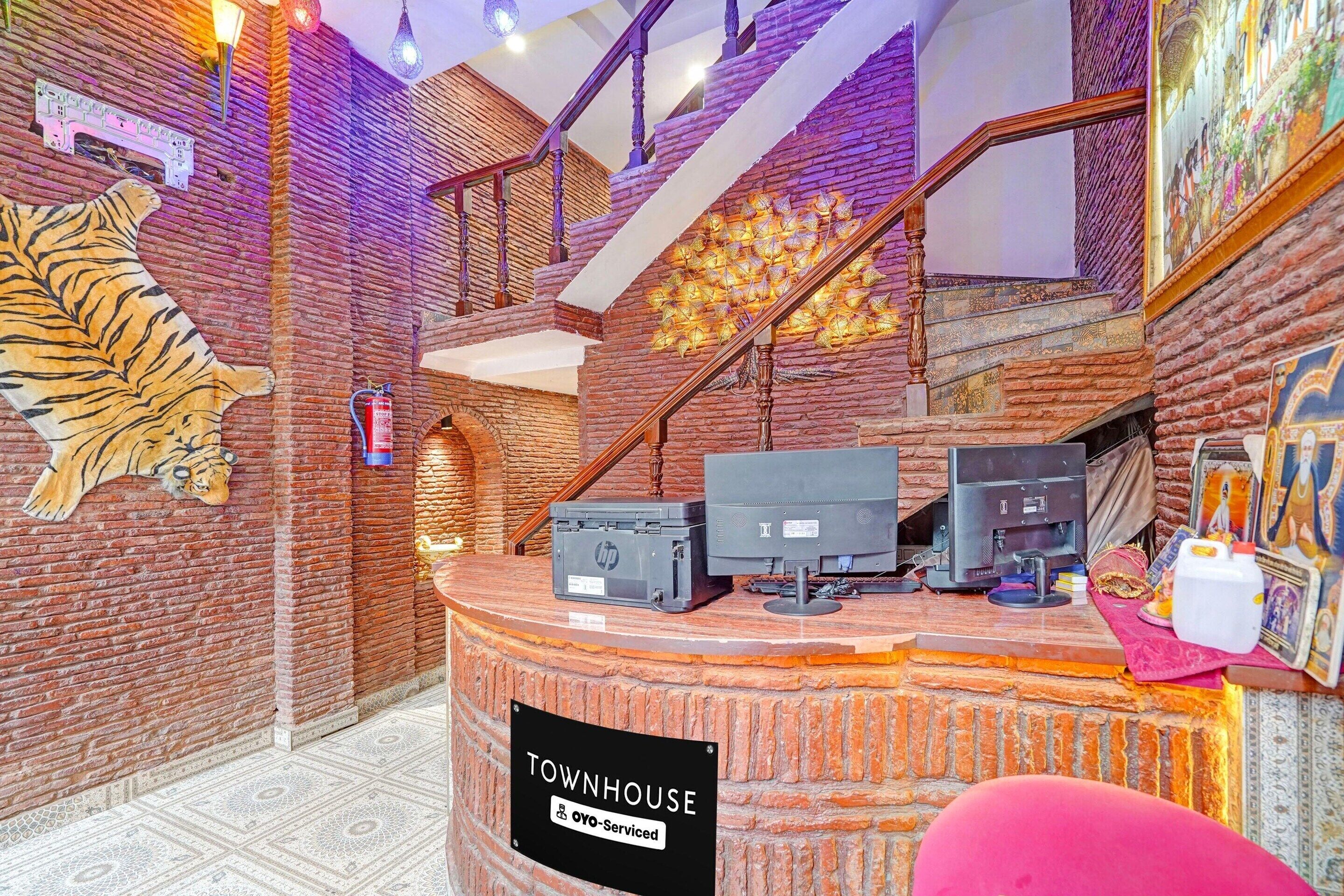Een receptiegedeelte met een bakstenen muur, een tijger muurschildering, een trap en een bordje dat aangeeft dat het wordt beheerd door OYO.