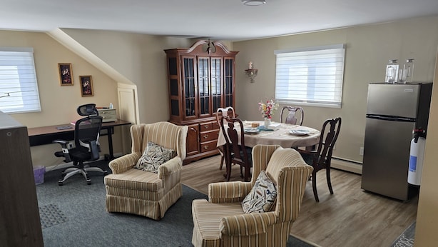 A dining area with a wooden table, chairs, and a refrigerator.