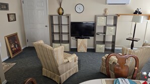 A living room with striped armchairs, a television, a clock, and a panda figurine.
