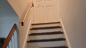 A staircase with wooden steps and white handrails, leading to a white door.