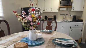 A dining table with a vase of flowers, placemats, and plates set for a meal.
