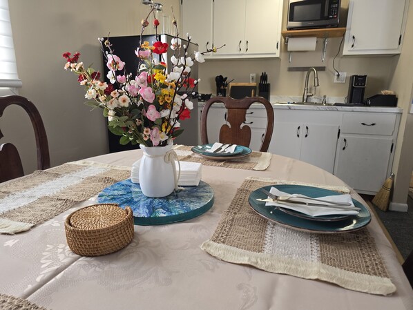 A dining table with a vase of flowers, placemats, and plates set for a meal.