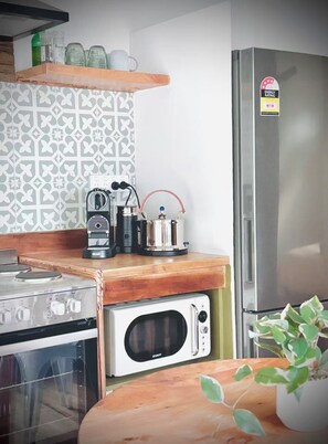 Una cocina con estufa, microondas, hervidor y refrigerador.