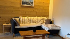 Una habitación con paneles de madera, un sofá, una mesa de centro y un cuadro en la pared.