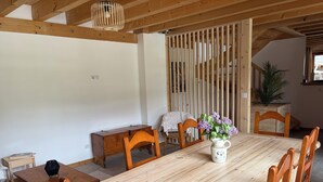 Una mesa de comedor de madera con sillas, un jarrón de flores y un mueble de madera pequeño.